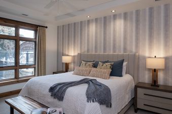 A cozy king bedroom in Buck Mountain 2 Bedroom One Steamboat Place 307 with a king-sized bed, striped accent wall, and large window.