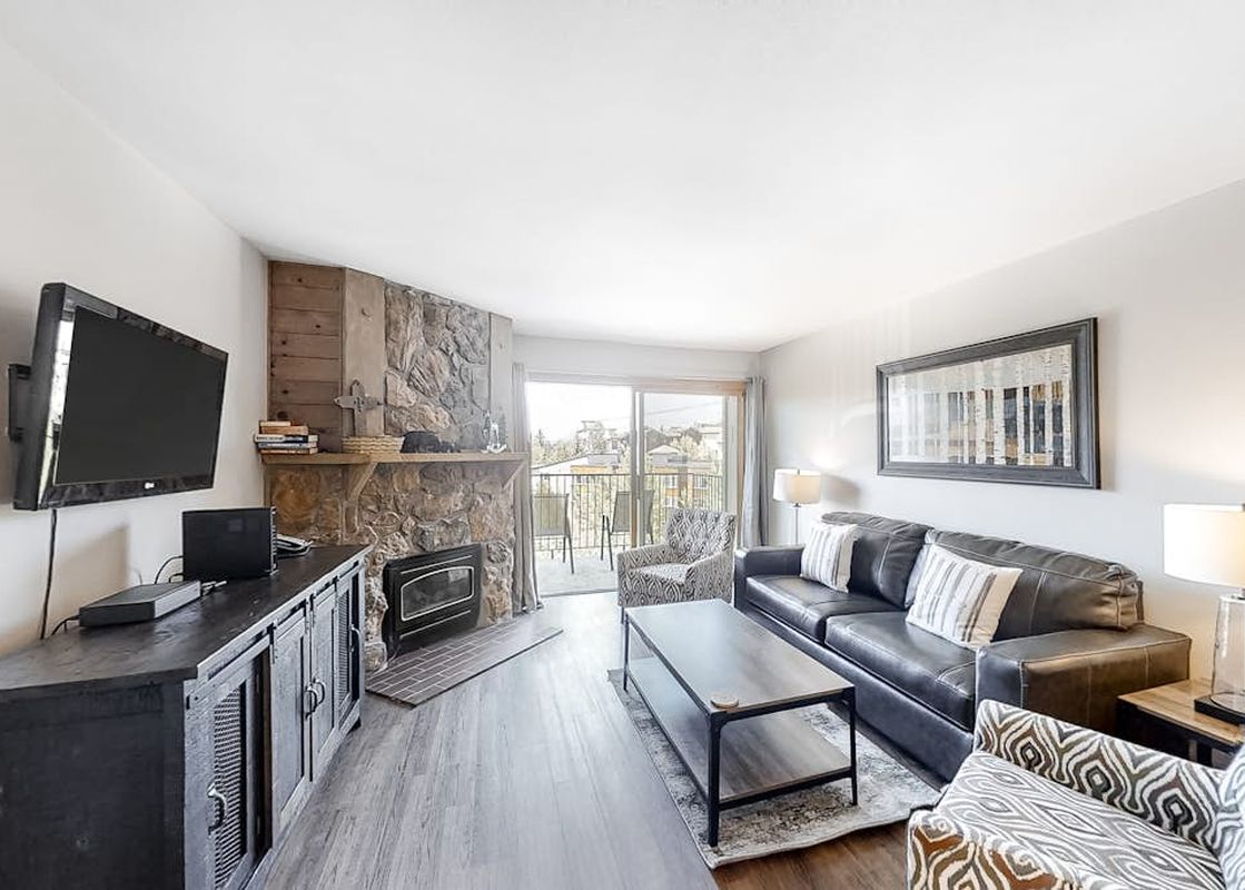 Cozy living room of Ski Inn Condominium 221 with stone fireplace and leather sofa