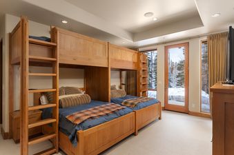Bunk room at Skyline Estate with custom-built wooden bunk beds and views of a snowy winter forest.