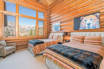 The Villas At Tristant 127 bedroom features rustic log walls, two beds, and a window with a mountain view.