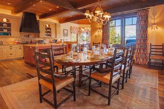 A rustic-chic open concept kitchen and dining area at 492 Golf Course Circle with a large wooden dining table set for guests.