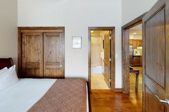The bedroom in Manor Vail 336 features a king-size bed, wooden floors, and a door leading to the bathroom.