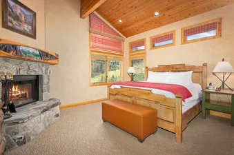 Trails End Lodge 18 features a fireplace and a king size bed with views of the mountains and forest.