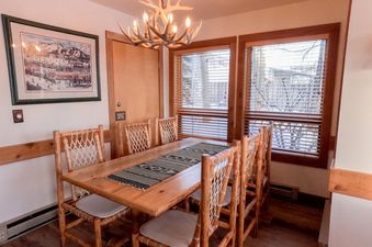 Rustic wooden dining table and chairs under an antler chandelier in Nez Perce D1.