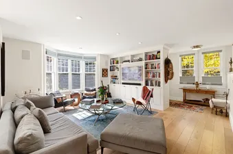 Comfortable living room with a large grey sofa, built-in shelving, and large bay windows in Park Place in Telluride.