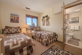 A cozy bedroom with twin beds and an attached bathroom in the Whiteridge A4 unit.