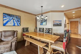 Dining area in Centrum 302 with a long wooden table, patterned chairs, and a metal chandelier.