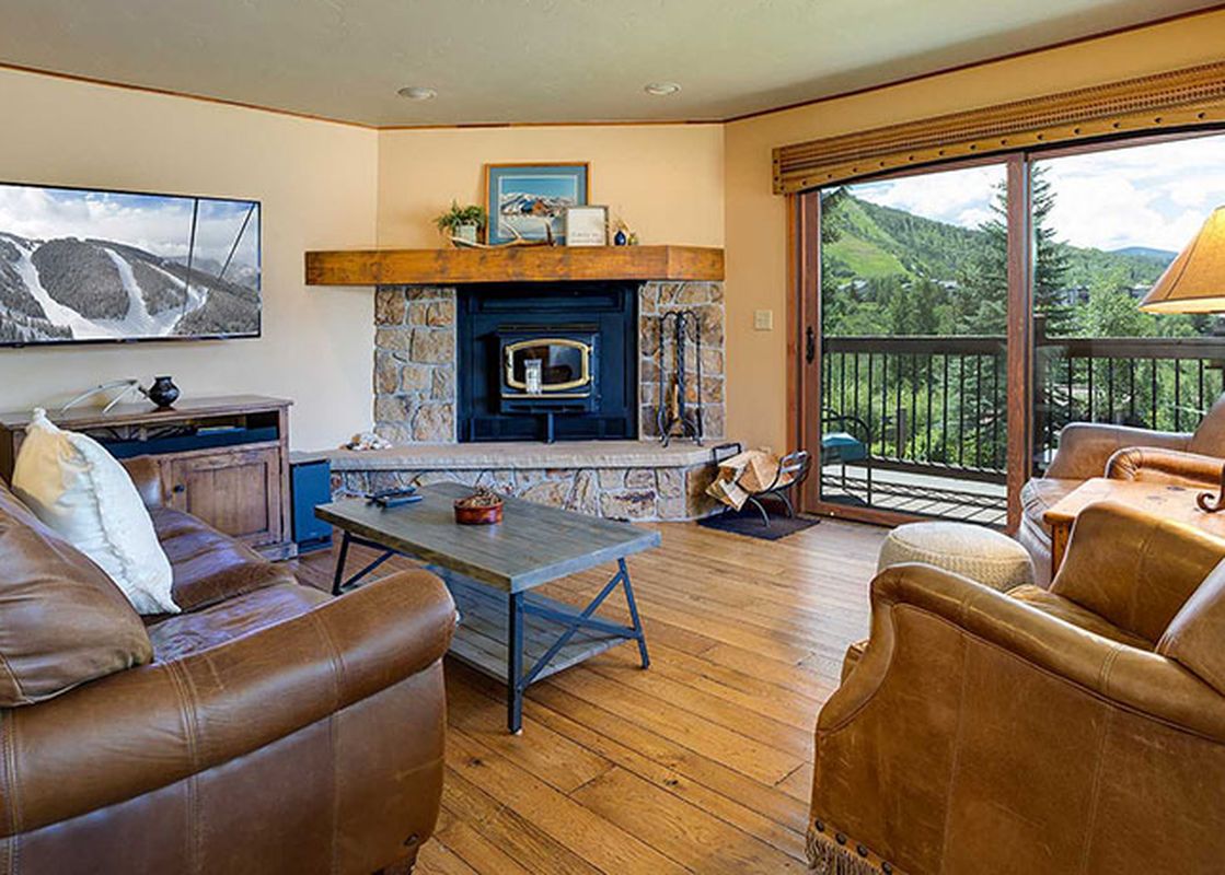 A spacious and inviting living room at the Ranch at Steamboat RA201, featuring a prominent stone fireplace, comfortable leather sofas, and a large window offering scenic mountain views.