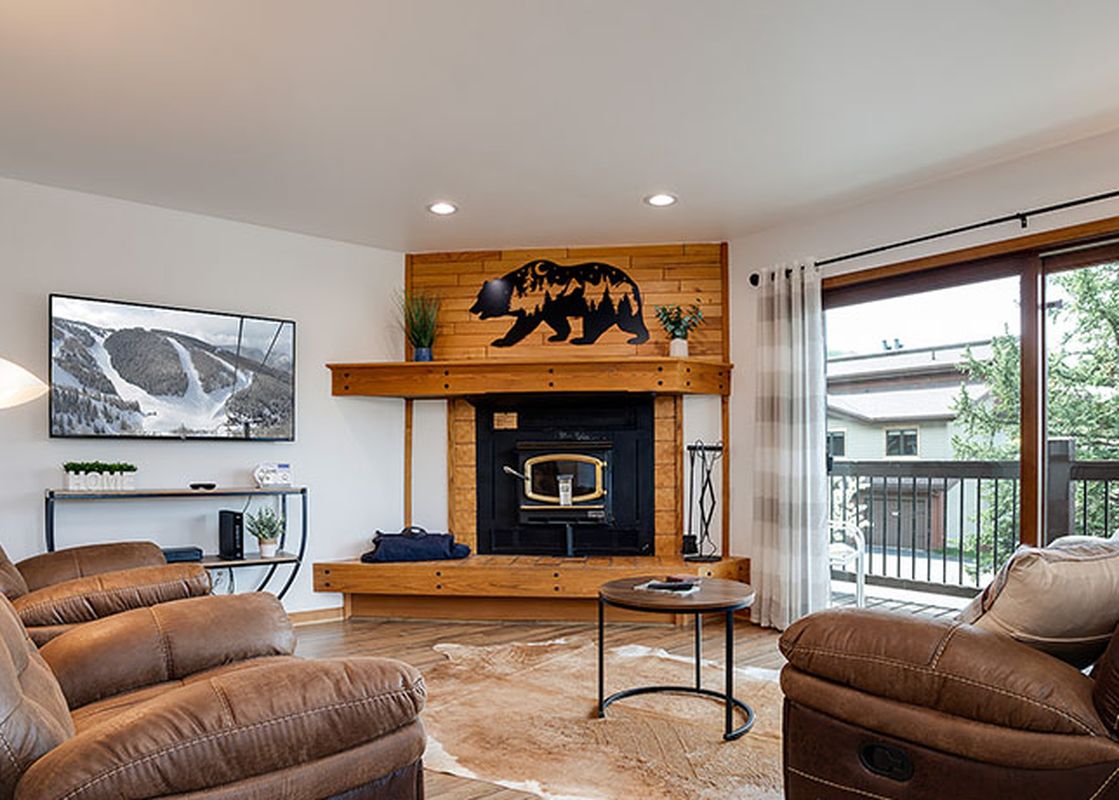 The rustic living area of the Ranch at Steamboat RA101 with a fireplace, comfortable recliners, and a view of the outdoors.