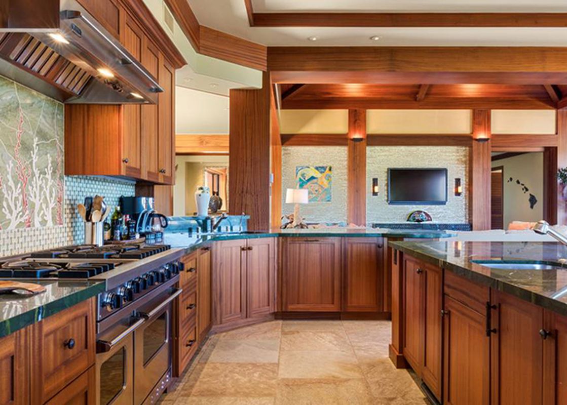A spacious and modern kitchen in Hale Hoaloha with dark wood cabinets and green countertops.
