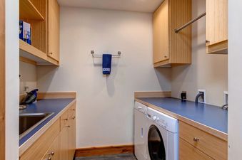 A functional laundry and utility room with wood cabinets, blue counters, and a white washing machine.