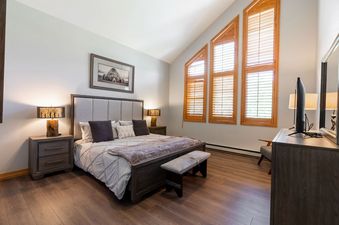 The primary bedroom at Strawberry Park 605 features a king-sized bed, dark wood furniture, and a neutral color palette.