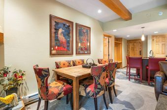 A dining room with a wooden table and chairs with floral upholstery.  The dining room is located in a modern vacation rental.