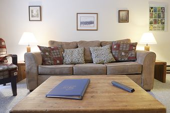 The living area at Beaver Village 1821 features a comfortable sofa with throw pillows, two end tables with lamps, a coffee table, and various wall decor.