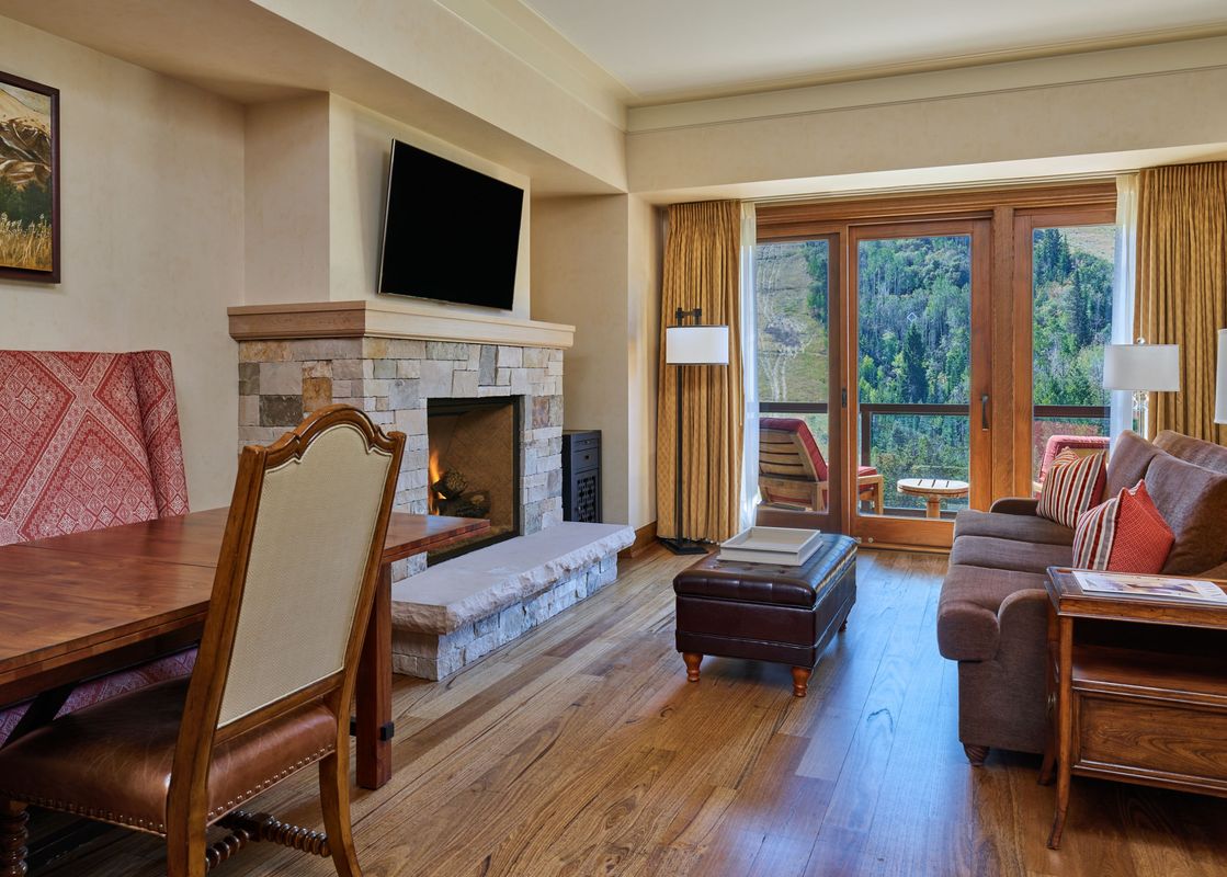A cozy living room with a fireplace and a view of the mountains from a large window.