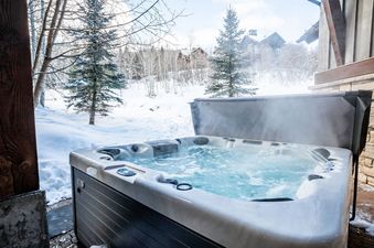 An inviting outdoor hot tub steams in the snow outside Canyons Red Pine Chalet 91.