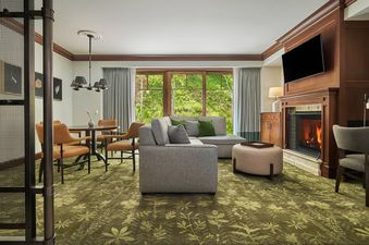The Montage Deer Valley Suite Resort View with Fire Pit features an inviting living space, complete with a cozy fireplace, comfortable sofa, and dining area.