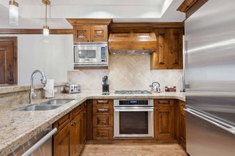 Modern kitchen with wood cabinetry and stainless steel appliances at The Aspen 12B.