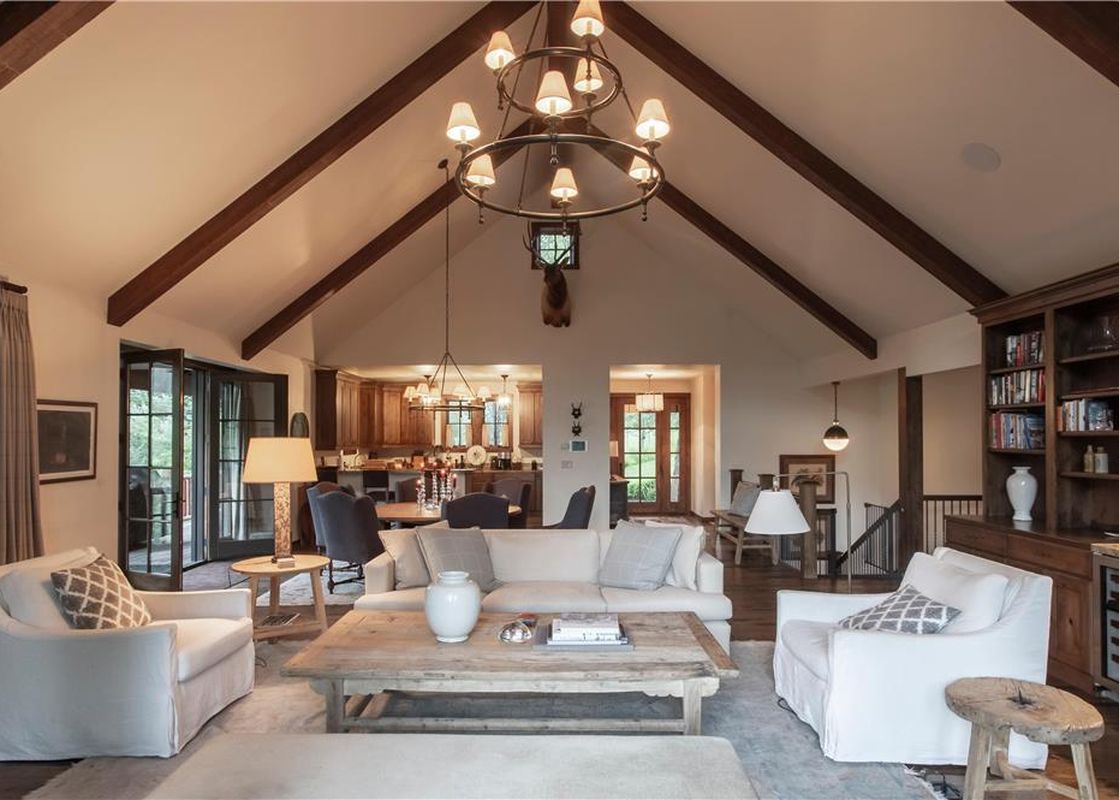 A spacious open-concept living room at the Martin Creek Cottage with vaulted ceilings, exposed wooden beams, comfortable seating, and an adjacent kitchen.