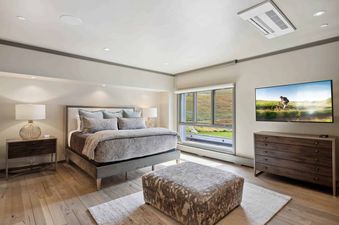 A serene bedroom at Village Hall 09 features a comfortable bed, stylish furnishings, and a large window offering scenic outdoor views.