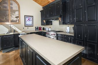 A spacious kitchen with rustic black cabinets and a large central island at Buffalo Park 3.