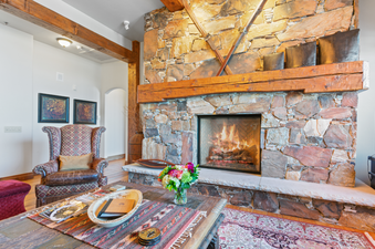 Cozy living area of Grand Lodge Three Bedroom Deluxe 206 with a large stone fireplace and a comfortable armchair.