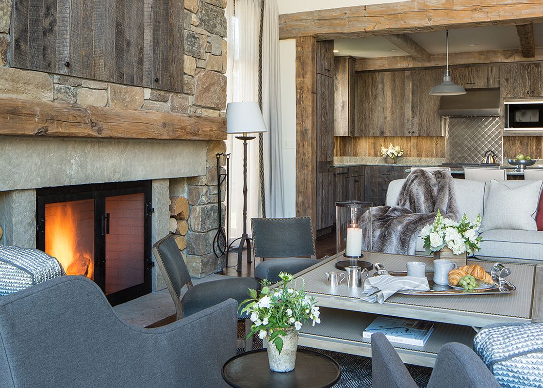 A cozy living room and kitchen area with a large stone fireplace and rustic wooden accents.
