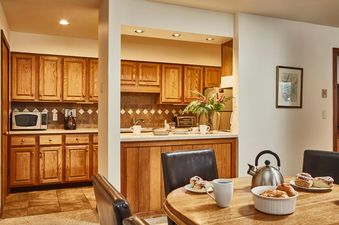 Fully equipped kitchen with wooden cabinetry and a set dining table at Teewinot B3.