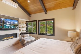 A bedroom with a large bed, a fireplace, and a view of the mountains through the window.