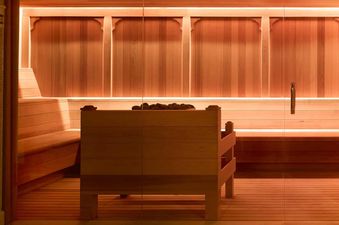 The interior of a sauna at Montage Deer Valley One Bedroom Residence, featuring wooden benches and walls, with an illuminated heater in the center.