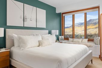 A serene bedroom at Meadows Crossing with a king bed, mountain views, and ski lift artwork.