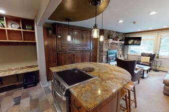 Kitchen with granite countertops, stainless steel appliances, and a fireplace in the living room