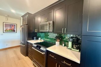 Modern kitchen with dark cabinetry, green tile backsplash, and stainless steel appliances at Lodge at Steamboat F303.