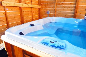 A private hot tub is set against a wooden slatted privacy fence.