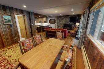 The dining room at Manor Vail 148A has a wood table with four chairs and a view of a fireplace.