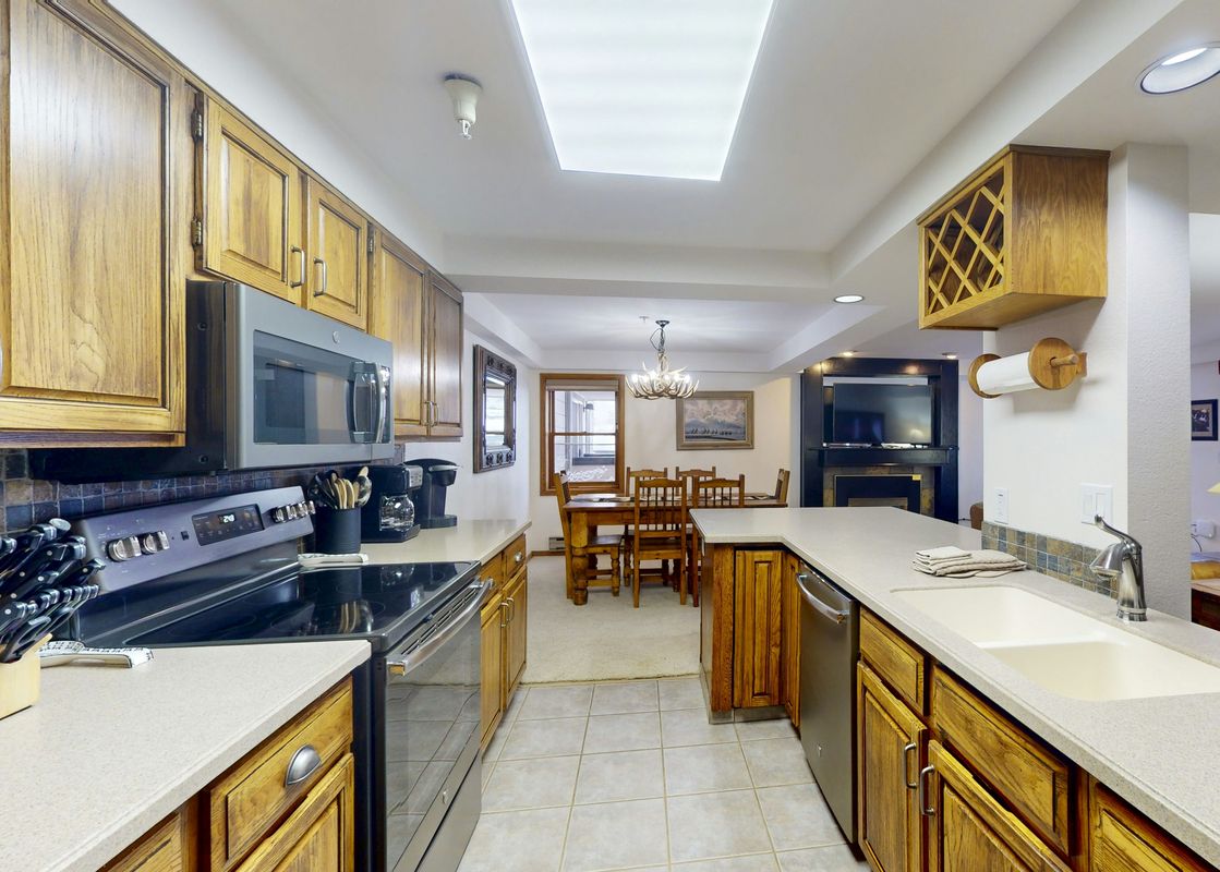 The kitchen at Torian Plum Plaza 202 features wooden cabinetry, stainless steel appliances, and a tiled backsplash, offering a functional and stylish space.