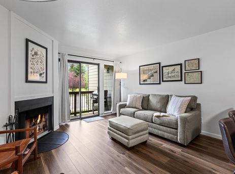 Cozy living room in Snowcrest 207 with a fabric sofa, fireplace, and sliding doors to a balcony.