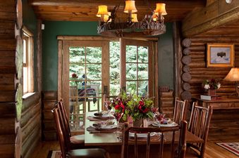 A rustic dining table set with elegant dinnerware and floral centerpieces inside The Cabin in Jackson Hole.