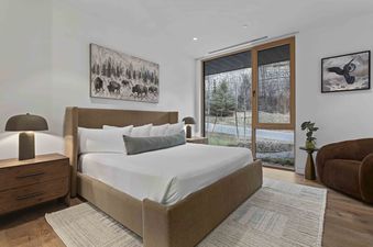 Cozy bedroom in Founders 1402 with a king-size bed, wildlife art, and a large window looking out onto a wooded landscape.
