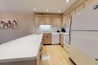 A fully equipped kitchen at Westwind 402 with light wood cabinets, white appliances, and a large counter island.