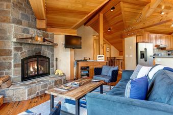 Cozy living area with stone fireplace, blue sofas, and rustic wood finishes at Skyline Jackson Hole.