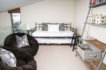 The comfortable bedroom in Landmark 705 features a full bed with a trundle and an inviting brown plush armchair, ideal for relaxation.