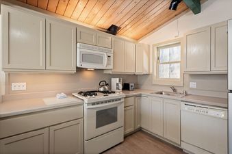 Well-equipped kitchen in Shadow Mountain Unit 19 featuring beige cabinetry, a gas stove, a dishwasher, and a wooden paneled ceiling.