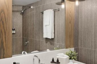 A modern bathroom vanity at the Gravity Haus JH Deluxe Loft, featuring a white countertop, sleek fixtures, and industrial lighting.