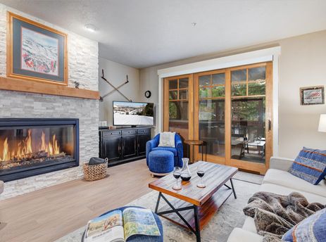 Cozy living room in Town Pointe A102 with a fireplace, comfortable seating, and sliding glass doors to the balcony.