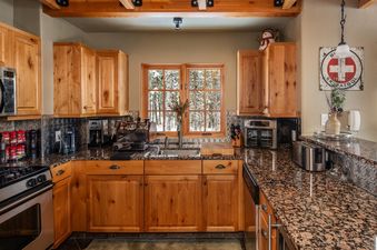 The kitchen at Moonlight Basin 2 Mountain Home features stainless steel appliances, granite countertops, and wooden cabinets.