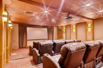 A community media room with leather reclining theater chairs and a large projection screen.