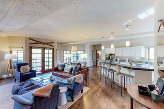 The living room of Westermere 310 features a leather couch, a large coffee table, two armchairs, and a large window with a view of the outside.