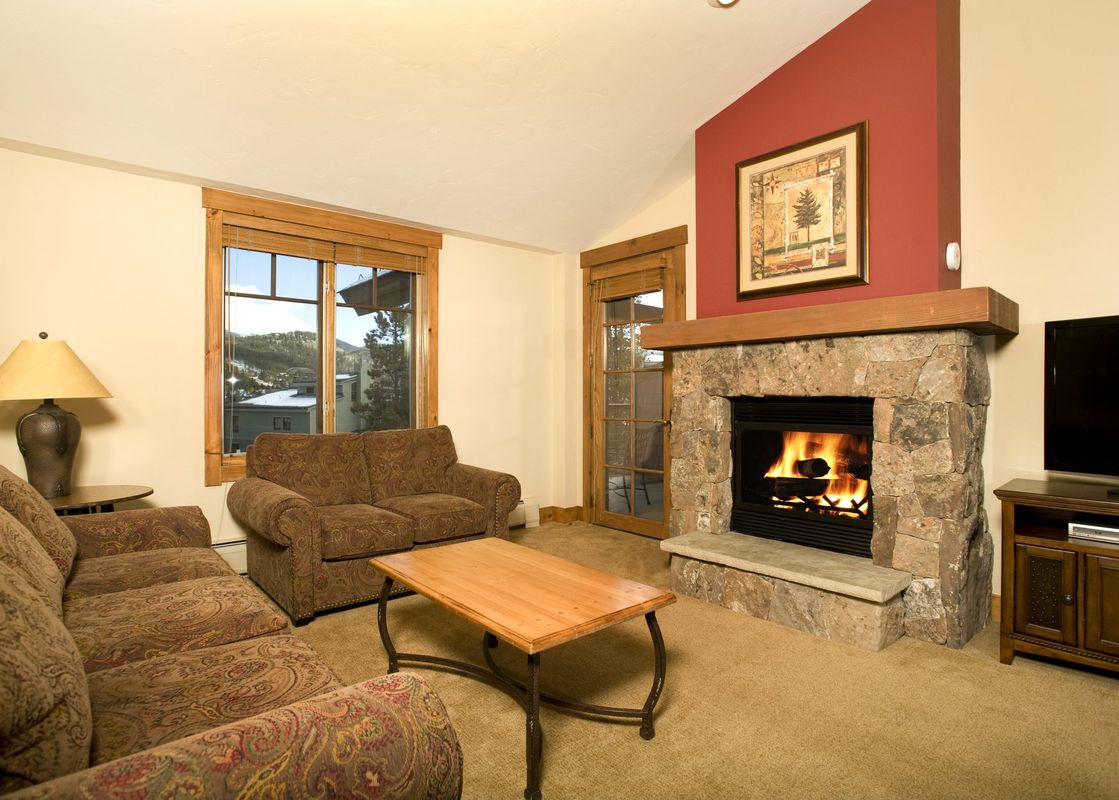 The cozy living room of the Mountain Thunder 2 Bedroom Condo featuring a stone fireplace and comfortable sofas.