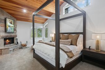Master bedroom at Twin Pines 5 featuring a dark wood four-poster bed and a cozy stone fireplace.